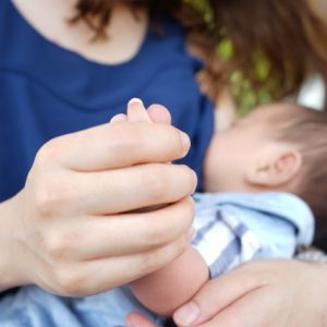赤ちゃんの手をやさしく握る母親
