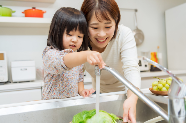 キッチンでお母さんと野菜を洗う子ども